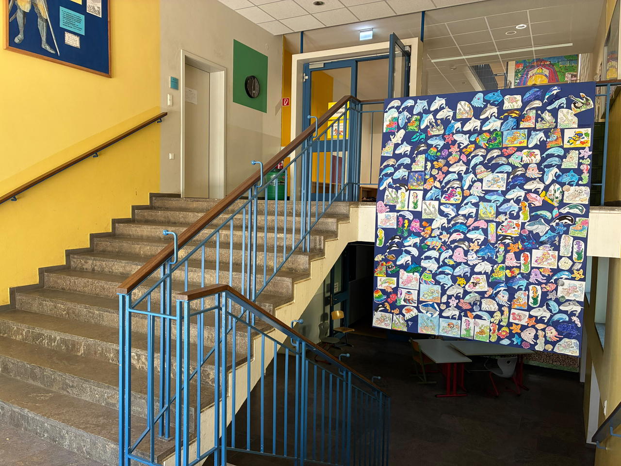 Eine Wand im Treppenhaus, über und über bedeckt mit gemalten Meerestieren der Kinder